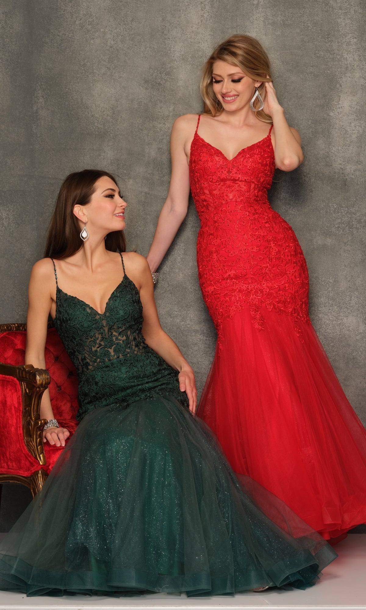 Two women pose before a gray backdrop; one sits on a red chair in a formal dress, while the other stands gracefully in the Dave & Johnny A10625 Long Lace Mermaid Prom Dress.